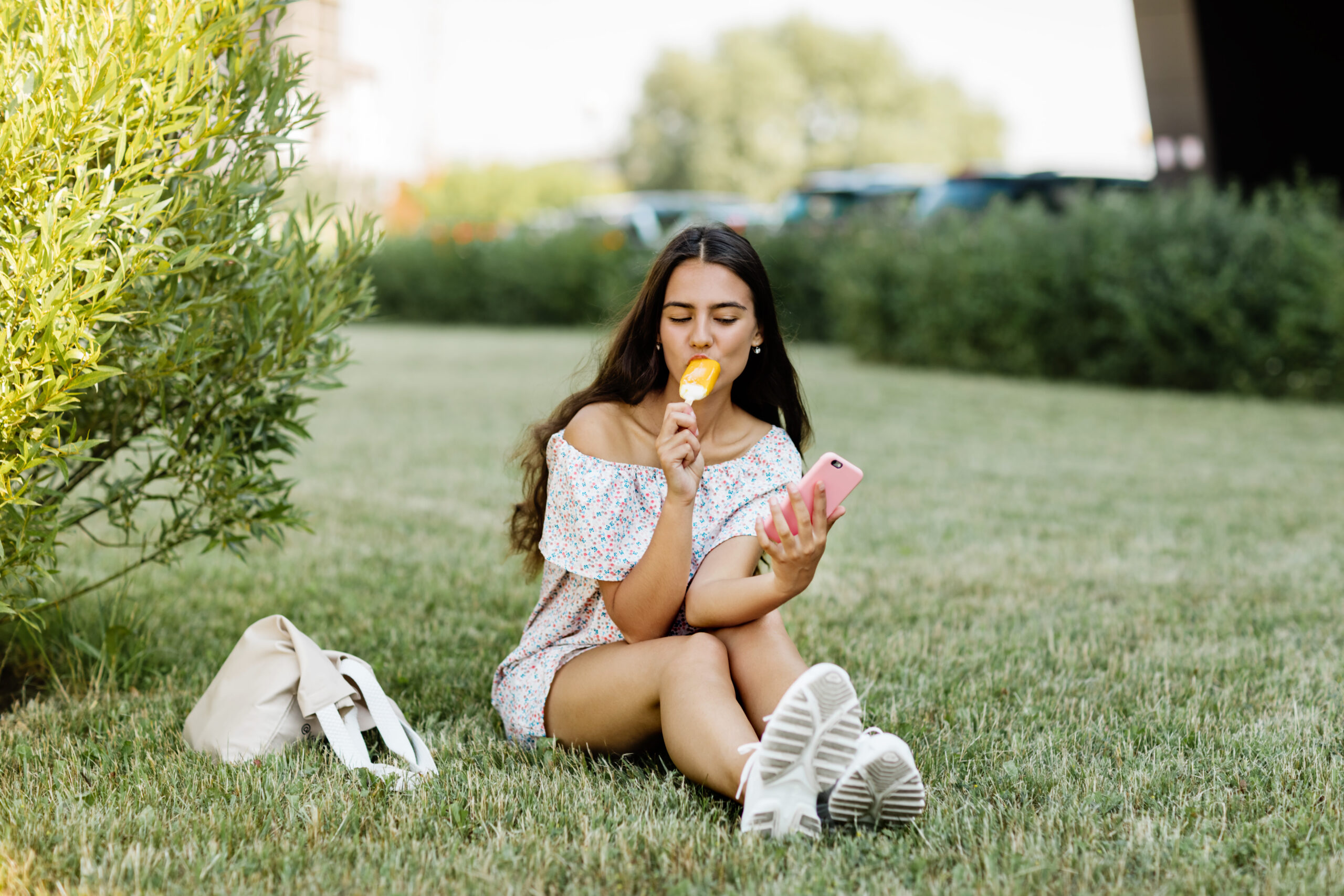 芝生でアイスを食べる女性